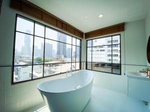 邦拉SO Zen Hotel Silom Bangkok的带窗户的浴室内的白色浴缸