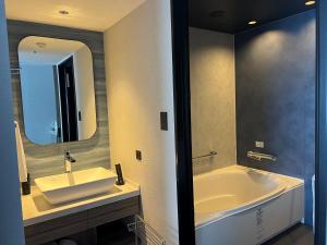 别府Grand Mercure Beppu Bay Resort & Spa的带浴缸、水槽和镜子的浴室