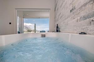 科孚镇Pelithea Family Aparthotel by Hotelius的浴室设有热水浴池,提供蓝色的水