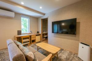 茅野小水鸟酒店的客厅配有沙发和墙上的电视