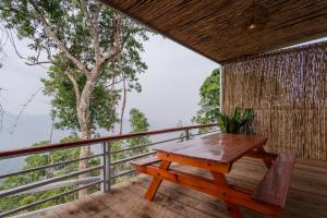 Kampong SeilaRomhaey Kirirom Resort的木桌和长凳,位于带树的阳台