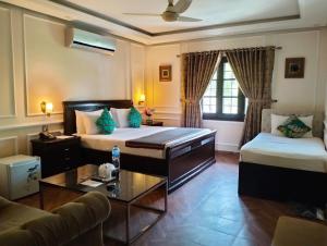 伊斯兰堡Riviera Courtyard Guest House Islamabad的一间带两张床和一张沙发的客厅