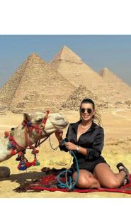 开罗Falcon pyramids inn的坐在金字塔前骆驼旁的女人