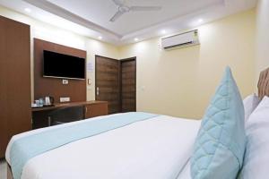新德里Hotel Mannat at Paschim Vihar的一间卧室配有一张床、一张书桌和一台电视。