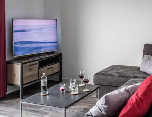 哈夫克鲁格Neue Liebe Haffkrug 5 - Meeresstern的客厅配有电视和葡萄酒
