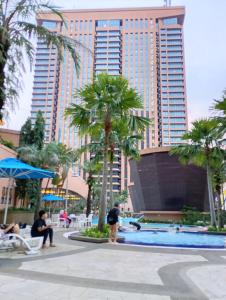 吉隆坡Ayan Service Suite At Times Square的一座棕榈树度假村泳池和一座高高的建筑