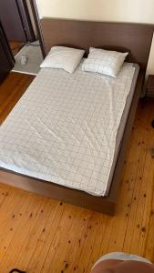 塞萨洛尼基Friendly guest house的铺有木地板的一张带白色床单和枕头的床