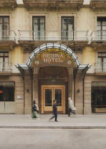 巴塞罗那Hotel Regina Barcelona的两个人在酒店前行走