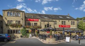 霍姆弗斯The Old Bridge Inn, Holmfirth, West Yorkshire的大楼前的餐厅,配有桌子和遮阳伞