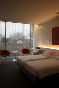 科特赖克D酒店的一间卧室配有一张床和两把椅子,并设有一个大窗户