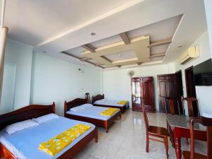 邦美蜀Manh Hung Hotel的一间卧室配有两张床和一张桌子及椅子