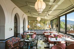 格拉纳达Alhambra Palace Hotel的餐厅设有桌椅和大窗户。