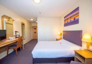 曼彻斯特V Lodge Manchester的配有一张床和一张书桌的酒店客房