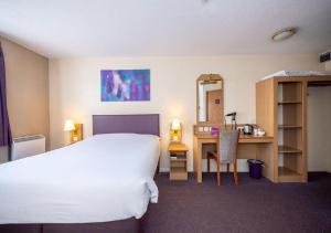 曼彻斯特V Lodge Manchester的酒店客房带一张床铺、一张书桌和一间卧室