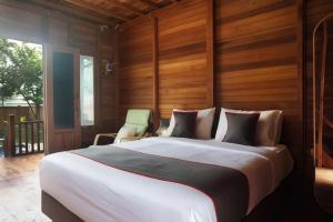 安耶尔Nemuru Villa Ubud Anyer的卧室配有一张白色大床和木墙