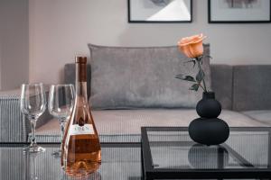 雅典Athens City Chic Apartment-2 bathrooms的一瓶葡萄酒和一张带玫瑰花的花瓶