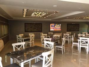Qaryat ash ShamālīGrand Plaza 6 Octobar的用餐室配有桌子和白色椅子