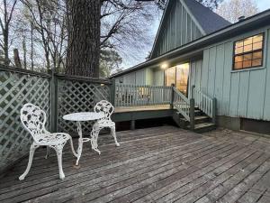 Doc's Cottage - A-Frame in Piggott, AR的木甲板上配有两把椅子和一张桌子