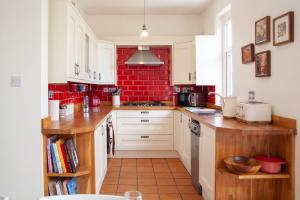 马伯斯Beautiful family home in Mumbles, with garden的厨房配有白色橱柜和红砖墙