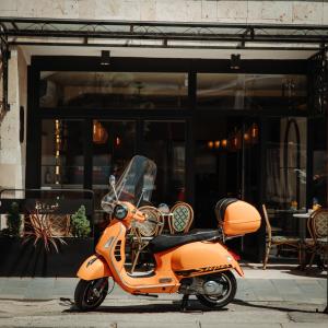 普里什蒂纳In Town Boutique HOTEL的停在大楼前的一辆橙色摩托车