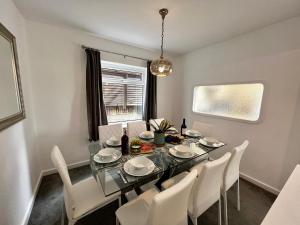 卡迪夫Spacious Family home in great location in Cardiff的一间设有玻璃桌和白色椅子的用餐室