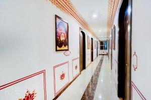 阿格拉Hotel Sahibs Royal Ville - Elegance by the Taj的墙壁上挂有白色墙壁和绘画的走廊
