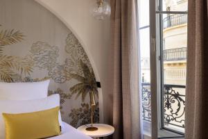巴黎最佳西方爱丽舍巴萨诺酒店的一间卧室配有一张带黄色枕头的床和窗户