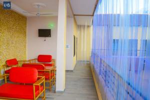 Abomey-CalaviCOMPLEXE HOTELIER LA BONTE ( CHB )的一间设有红色椅子和墙壁的等候室
