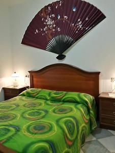卡斯特尔萨多Beach Apartments Costa dei Venti的卧室配有一张绿色的床,墙上装有风扇