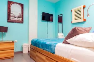 威廉斯塔德Bed & Bike Curacao的一间带蓝色墙壁、一张床和电视的卧室