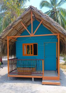 格兰德岛Hotel Las Casitas De Mar Adentro的海滩上带茅草屋顶的蓝色房屋