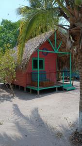 格兰德岛Hotel Las Casitas De Mar Adentro的海滩上一座红色房子,有茅草屋顶