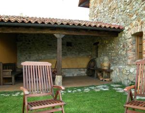 Robledo de la GuzpeñaLa Venta Del Alma的一座带两把椅子的庭院和一座石头建筑