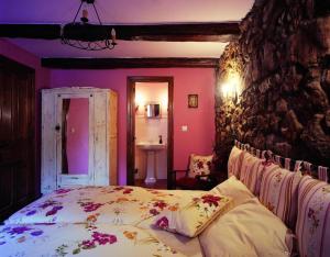 Robledo de la GuzpeñaLa Venta Del Alma的一间卧室设有一张床和石墙