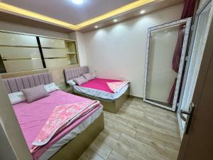 Al Ḩammādشاليهات مارينا دلتا ولاجونز的配有粉红色床单和镜子的客房内的两张床