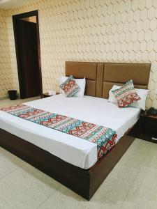 新德里Hotel Ambience Palace Near IGI Airport Delhi的卧室配有一张带白色床单和枕头的大床。