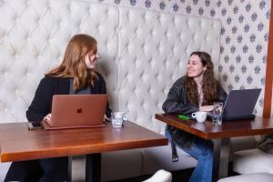 法尔肯堡Hotel 1711的两名妇女坐在桌子上,手提电脑