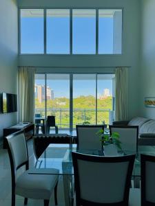 亚松森Luxury modern duplex apartment Villa Morra Asunción的客厅配有桌椅和大窗户
