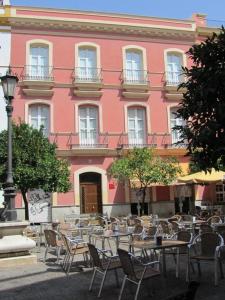 塞维利亚圣安德烈斯公寓酒店的粉红色的建筑,前面设有桌椅