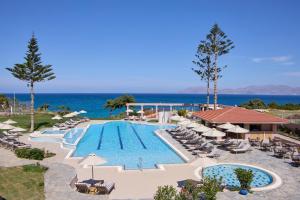 马斯蒂查里Ammos Luxury Resort的享有带椅子和遮阳伞的度假村游泳池的顶部景致