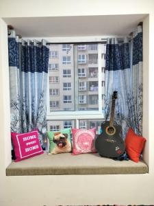 班加罗尔SOLACE Premium 3BHK Apartment Manyata Tech Park and Mall of Asia的窗户上的沙发、枕头和吉他
