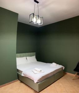 地拉那Tirana Rooms的绿色卧室配有带2条毛巾的床