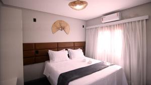 路易斯科雷亚Pousada Encantos do Coqueiro的一间卧室配有一张带白色床单的床和一扇窗户。