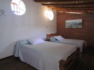 巴里查拉Casa Yerbabuena- Rustiko的一间卧室设有两张床和砖墙