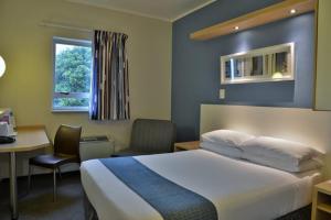 开普敦Road lodge Hotel Cape Town International Airport -Booked Easy的配有一张床、一张书桌和一扇窗户的酒店客房
