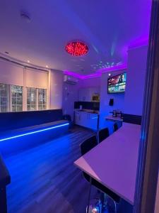利物浦19 Rodney Street Apartments的一间设有紫色灯和桌子的房间和一间厨房