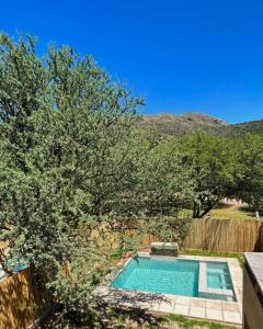 波特雷罗德洛斯弗内斯MONTEARENA POTRERO DE LOS FUNES的一座带树木和围栏的庭院内的游泳池