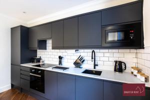 泰晤士河畔里士满1 Bedroom Apartment - Central Richmond-upon-Thames的厨房配有黑色橱柜、水槽和微波炉