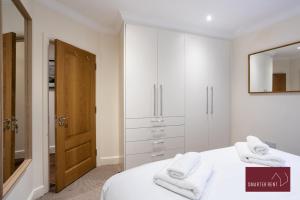 泰晤士河畔里士满1 Bedroom Apartment - Central Richmond-upon-Thames的白色卧室,床上配有白色毛巾