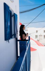 米克诺斯城Eleanna's Mykonos的站在窗外的阳台上的女人